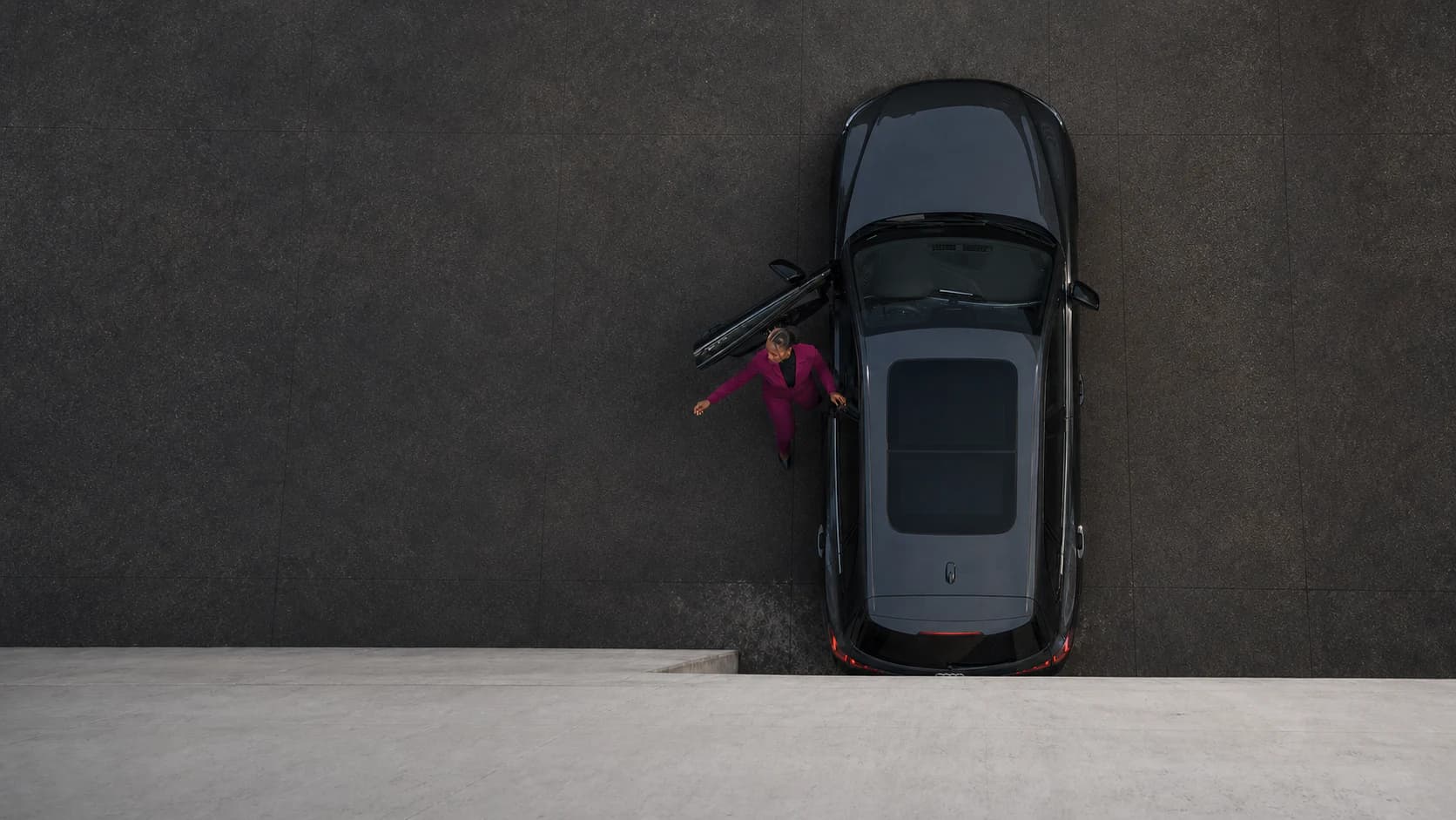 Authorized dealership employee using a phone beside an Audi on a dark studio floor.
